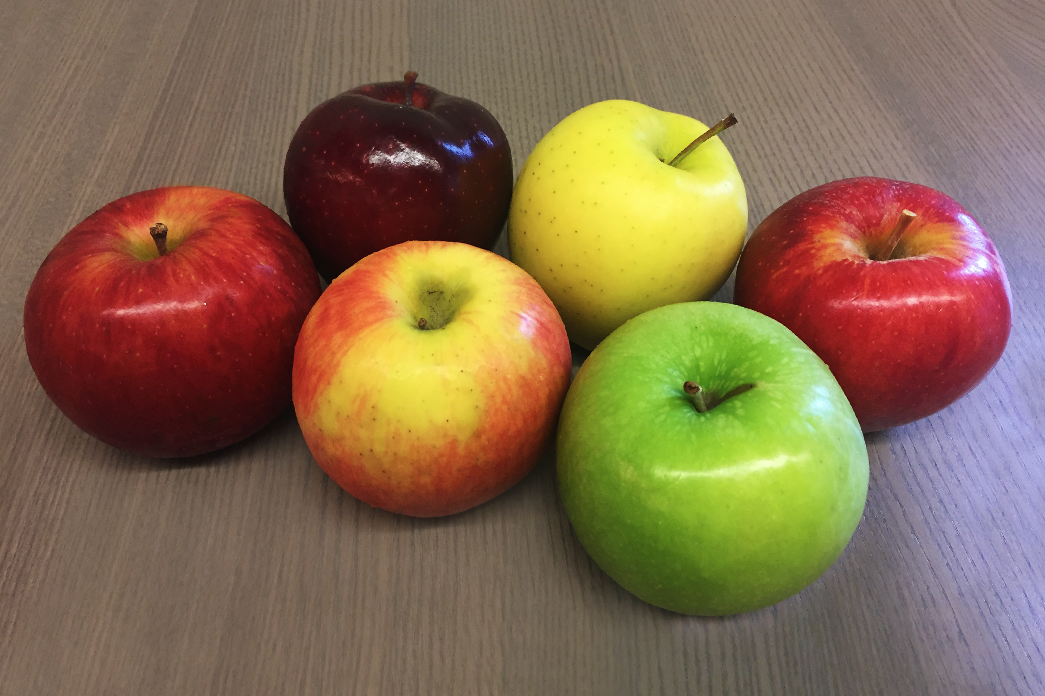 Several apple varieties in different colors sitting on a table.