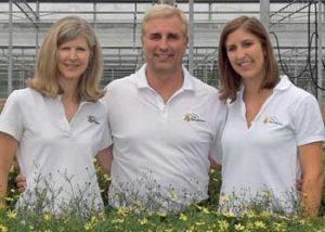 group of three people standing with flowers