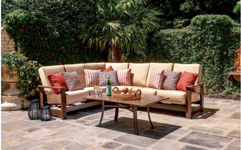 patio furniture sectional with orange pillows on stone patio