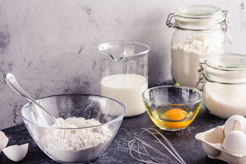 an egg sits in a glass dish and a bowl of flour sits next to it