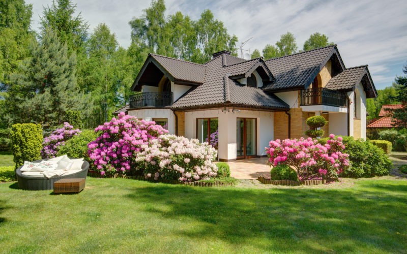 A home surrounded by beautiful landscaping including shrubs.