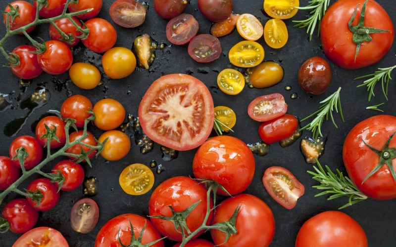 A variety of different types of tomatoes on a black background.