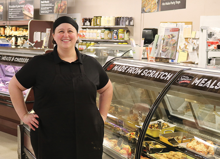 kitchen team member smiling in front of case