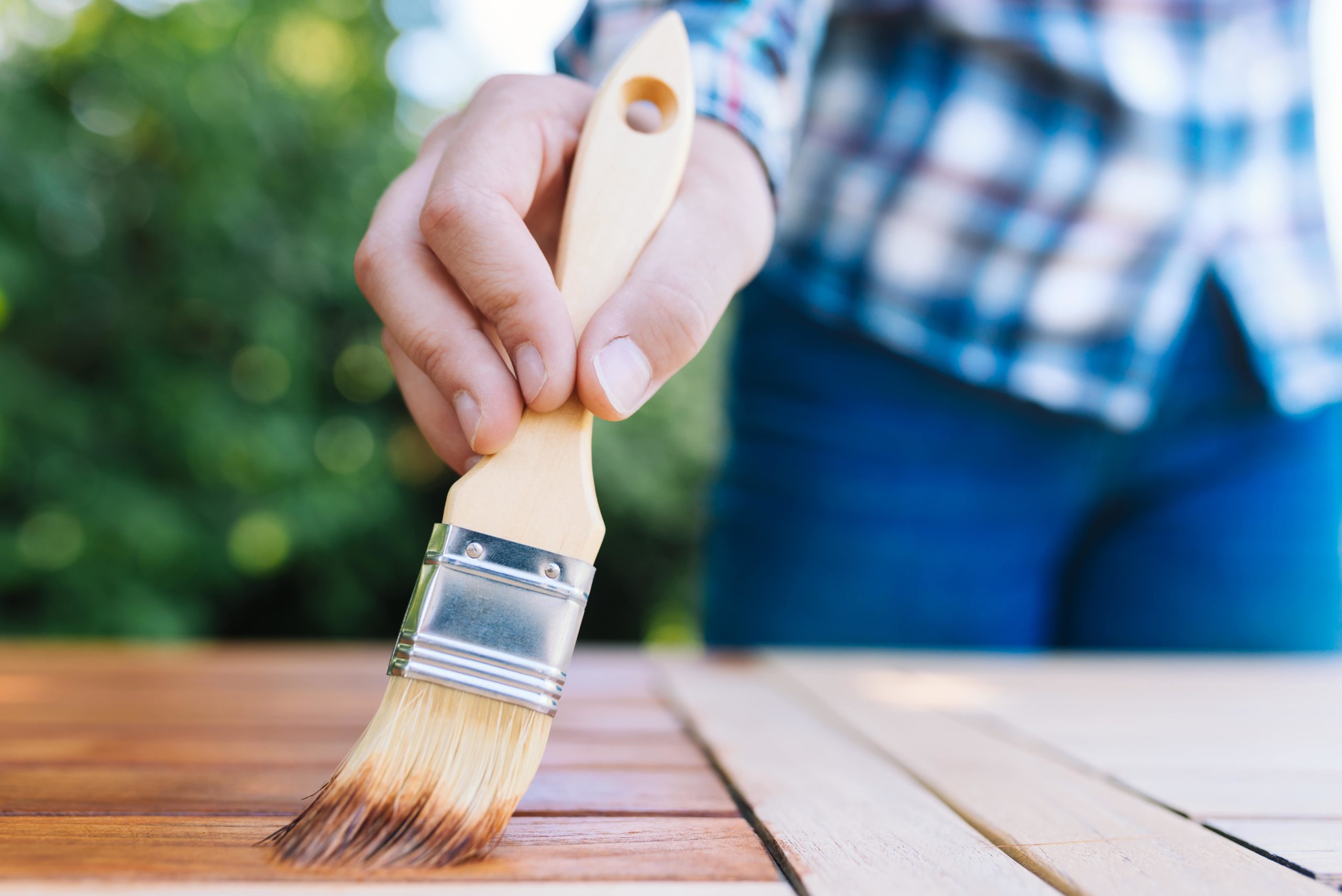 Homeowner sealing outdoor patio furniture.