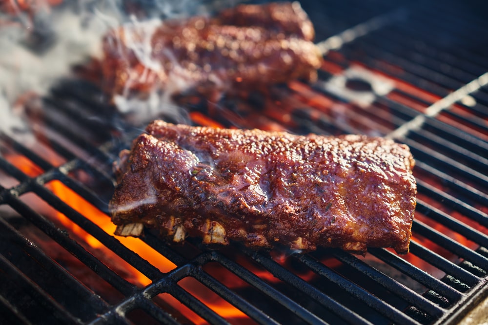 A rack of bbq ribs smoking on the grill.