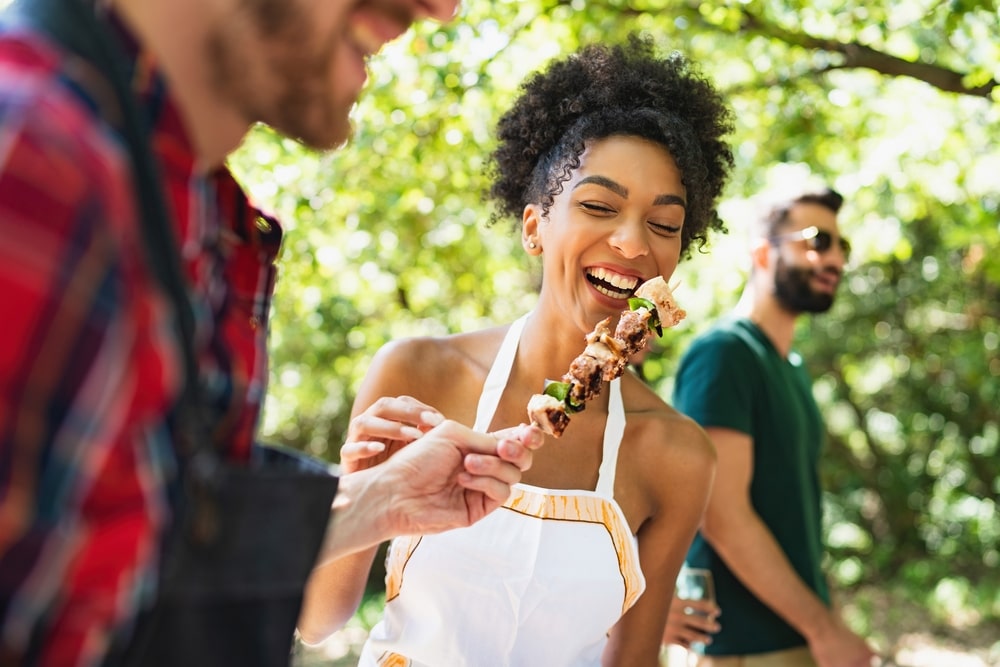 A woman enjoying a kabob, one of the best meats to grill.